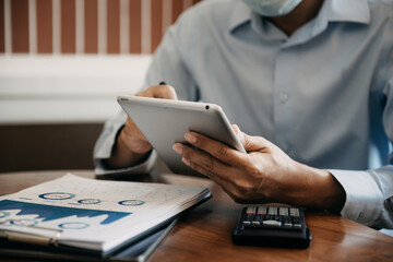 Male writes information businessman working on tablet  writing business plan while sitting in office.