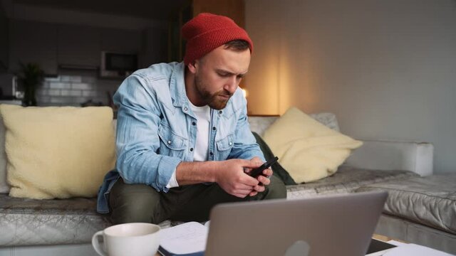 Caucasian male working from home recieving a funny text on cellular device 