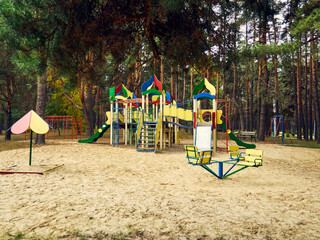 Obraz na płótnie Canvas colorful children's playground and sandbox, located among pine trees, in the park, there is no one