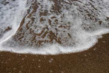 blurred abstract background of sea foam on sandy beach top view