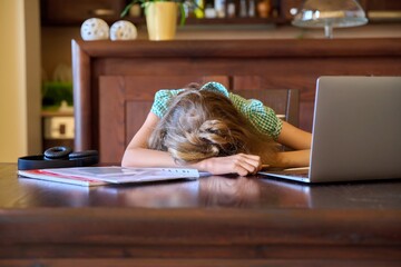 Tired girl student sleeping resting on the desk at home.