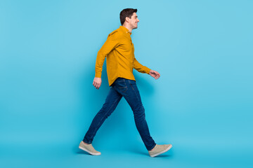 Full length profile photo of funny brunet boss man go wear yellow shirt jeans sneakers isolated on blue color background