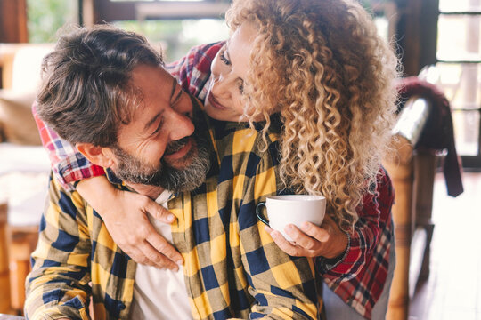 Man and woman at home smile and enjoy love relationship and friendship together. Cheerful adult people. Female with blonde curly hair and man with beard have fun and leisure time