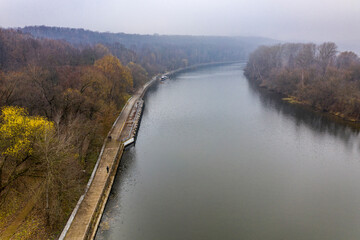 Naklejka premium autumn green river and yellow park on a cloudy autumn day filmed from a drone 