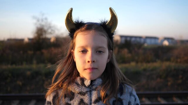 Cute kid little girl in devil horns posing face portrait