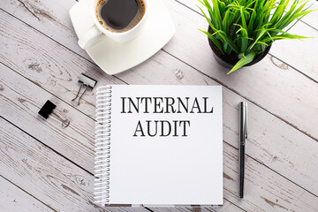 Cofee cup, notepad,pen on the wooden background. Business concept. Text INTERNAL AUDIT