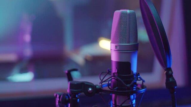 Close up shot of professional microphone with pop filter in recording studio with purple neon light