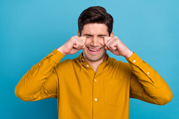 Photo of sad crying young guy dressed yellow shirt arms hands eyes isolated blue color background