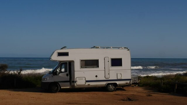 Santa Pola, Valencia, Spain - December 6, 2019: Autocaravan Chausson camping on sea shore. Sea waves moving in slow motion. Spain, Costa Blanca.