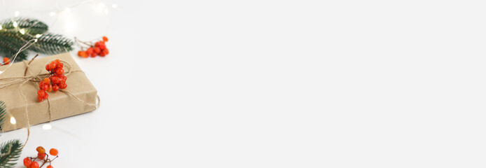 New Year's and Christmas. Gift in craft eco-friendly paper with a viburnum and pine branch on a white background. Lights and bokeh.