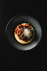 Stewed veal cheeks with mashed potatoes on plate on rustic wooden table dark background