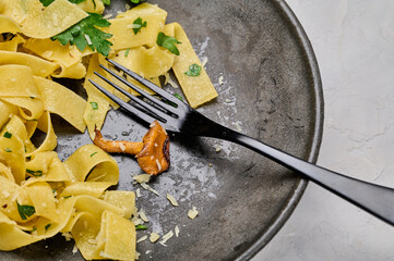 Plate of traditional pasta pappardelle with chanterelle mushrooms eaten not finished, fork on the...