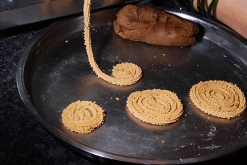 Homemade Preparation of Indian Traditional Snack Chakli consumed during diwali festival, a spiral shaped crisp deep fried snack, It is known as Chakali, Murkoo, Muruku and Murukku.