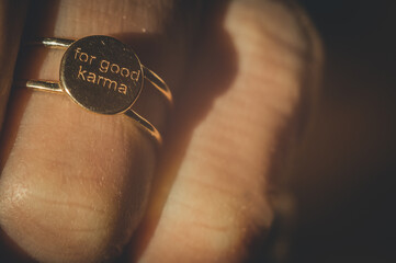 Gold ring engraved: For good karma. A gold ring on the finger of the hand close-up. Selective...