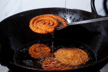 Homemade Preparation of Indian Traditional Snack Chakli consumed during diwali festival, a spiral shaped crisp deep fried snack, It is known as Chakali, Murkoo, Muruku and Murukku.