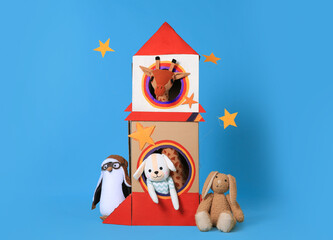 Cardboard rocket and different toys on light blue background