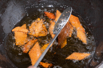 Homemade preparation of shankarpali a diamond shaped Traditional indian snack consumed during diwali festival in india by flattening dough with roller and deep fried in hot oil.