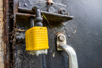 Closed yellow lock at black steel door with handle