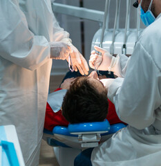 paciente es sometido a una intervención odontológica en una clínica dental - obrazy, fototapety, plakaty