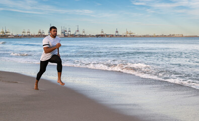 hombre fuerte atletico moreno indio pakistani corre hace deporte en una playa de arena con un fondo...