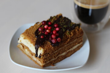 Honey cake and black coffee.  Cake decoration with chocolate and red berries
