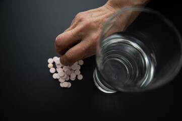 薬を多めに飲もうとして、つかんでいるところのアップ コピースペースあり