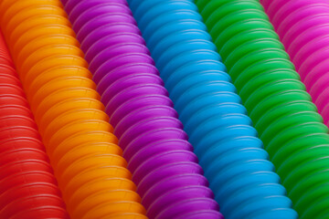 Rainbow colored anti-stress fidget pop tube sensory toy background. Close-up of trendy game with popular plastic flexible bright corrugated pipe.