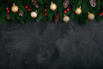 Christmas background with green fir branches, cones and golden and red decor.