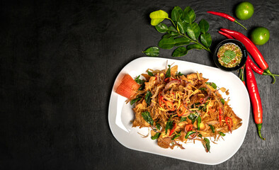Thai fried fish with fish sauce and many herbs. A delicious recipe from Asia and spices ingredients for cooking on dark black wooden table background, Thai food, Asian foods, Thailand restaurant menu
