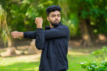 Young man stretches his arm, warming up before exercise