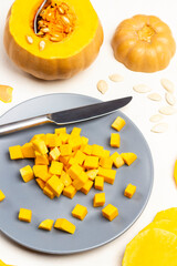 Small pieces of pumpkin and knife on gray plate. Spoon in pumpkin pulp.
