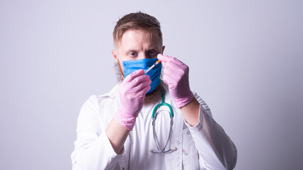 a young doctor in a mask holds an inzulin syringe