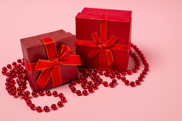 Red gift boxex and garland on pink background with copy space for text. For new year, christmas and holiday cards