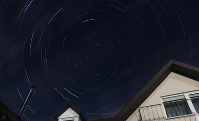 Star trails against the background of a village house - Powered by Adobe