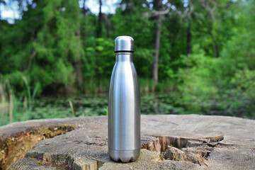 Steel thermo water bottle. Be plastic free. Zero waste. Copy space. Zero waste, no plastic. Water bottle on wooden stump in the middle of woods.