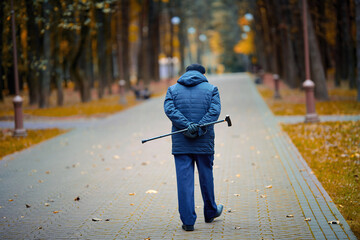 Elderly man walking with walking cane in hand behind his back. Old man with cane enjoying walk in...