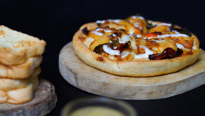 Italian pizza with some tasty topping on it served with other bread. a studio shot of a delicious food served on the wooden peel isolated on black.