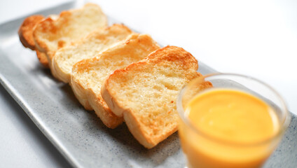 Fototapeta na wymiar the golden brown toasted bread served with a cup of cheese sauce. a typical of breakfast menu for western.