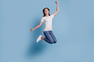 Portrait of funky stunning delighted lady jump raise fists look camera on blue background
