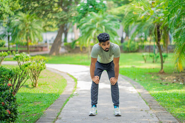 Tired young man runner taking a rest after running hard at the park