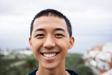 Young asian man smiling on camera outdoor - Focus on face