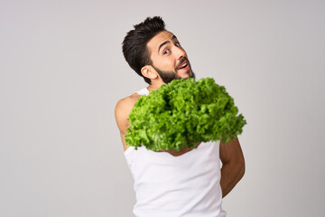 cheerful man in a white t-shirt lettuce leaves healthy food