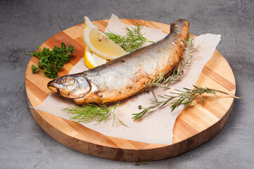 grilled river trout with lemon, rosemary on a wooden board