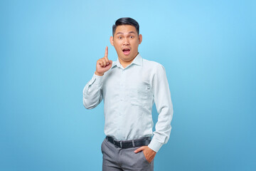 Fototapeta premium Excited young handsome businessman having a creative idea and looking camera on blue background