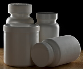 Medical pill bottles on timber bench with black background