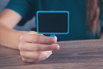 young woman holding a small blank board