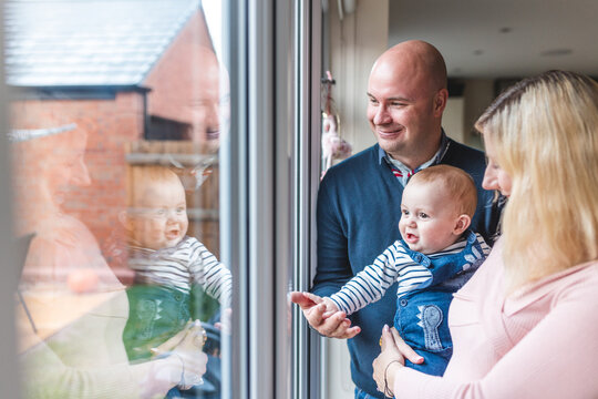 Happy family of three smiling and looking out of the window