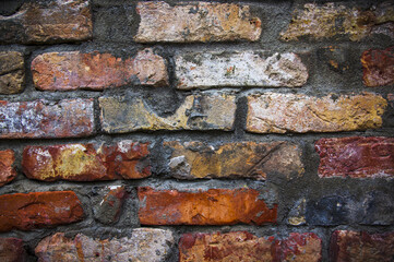 Grey white black red orange old vintage brick wall background. Rustic cemented dark brick house wall texture with grunge surface. Shabby Building Facade With Damaged Plaster. Aged weathered exterior