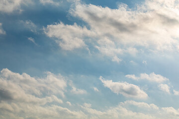 Blue sky with clouds and sun. High under with rays from the sun in the right corner of the frame
