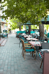 Vase with fresh flowers on a napkin, decorates a table of a street cafe on a summer day. Empty street cafe or restaurant tables with chairs on street
